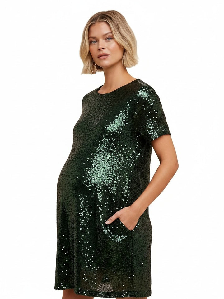 Mom & Me Boutique Gwennie shift dress in dark green sequin with short sleeves and side pockets on a pregnant model