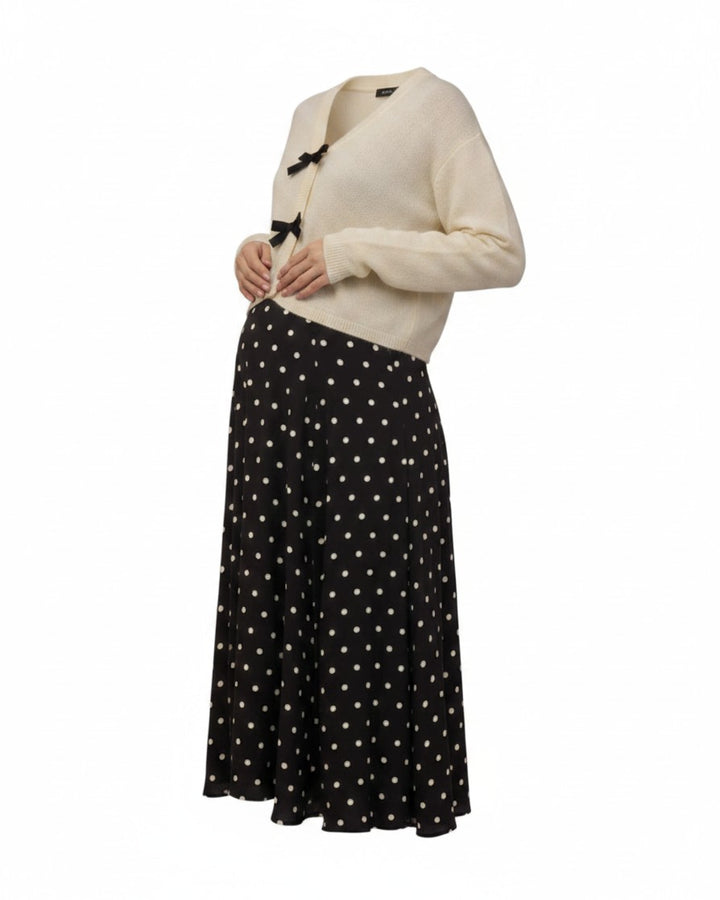 Mom & Me Boutique ivory knit cardigan featuring black bow closures, worn with a black and white polka dot skirt.