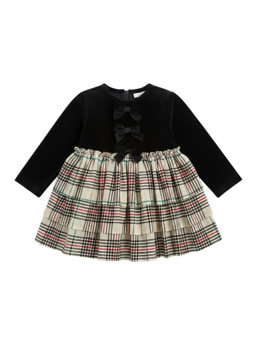 Mom & Me Boutique baby girls plaid skirted romper with a black velour bodice and tiered tulle skirt with bow accents.